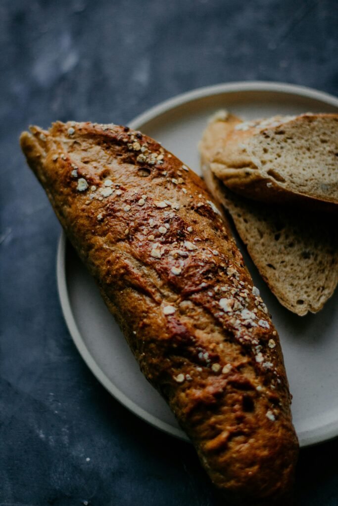 pexels photo 2067408 2067408 Close-up of homemade whole wheat bread with oats on a plate, dark background.