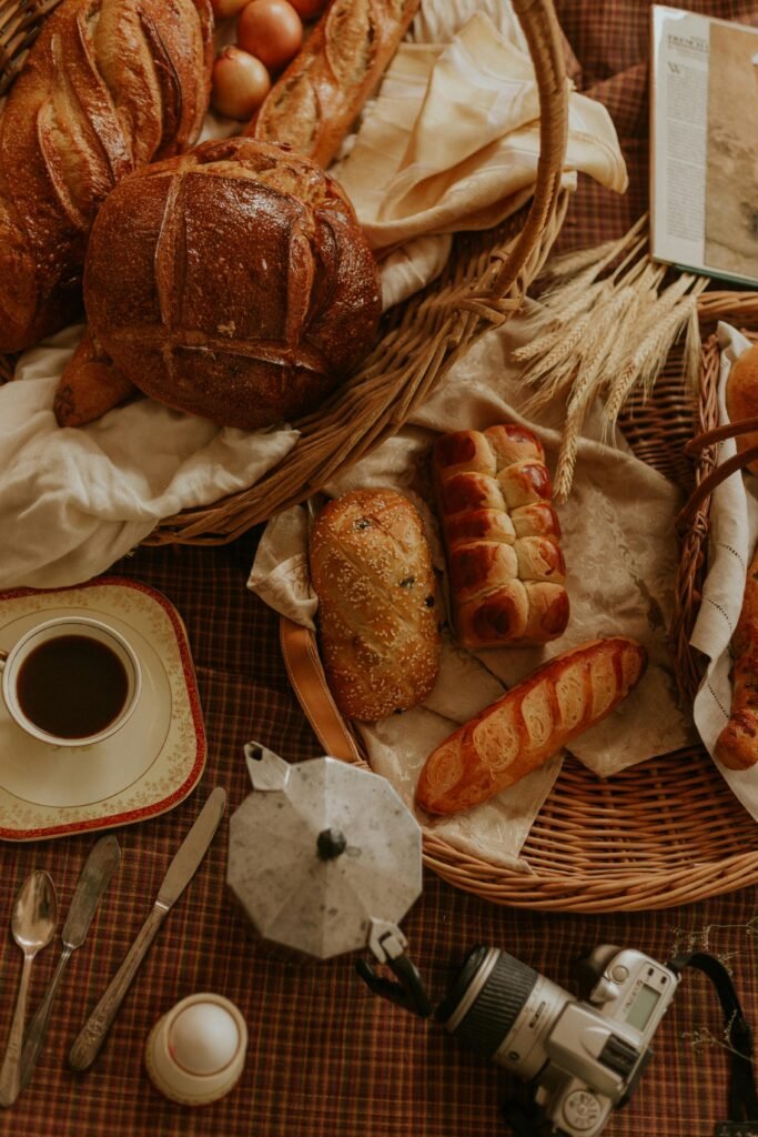 pexels photo 6966614 6966614 Warm rustic setting with fresh bread, a cup of coffee, and a camera on a checkered tablecloth.